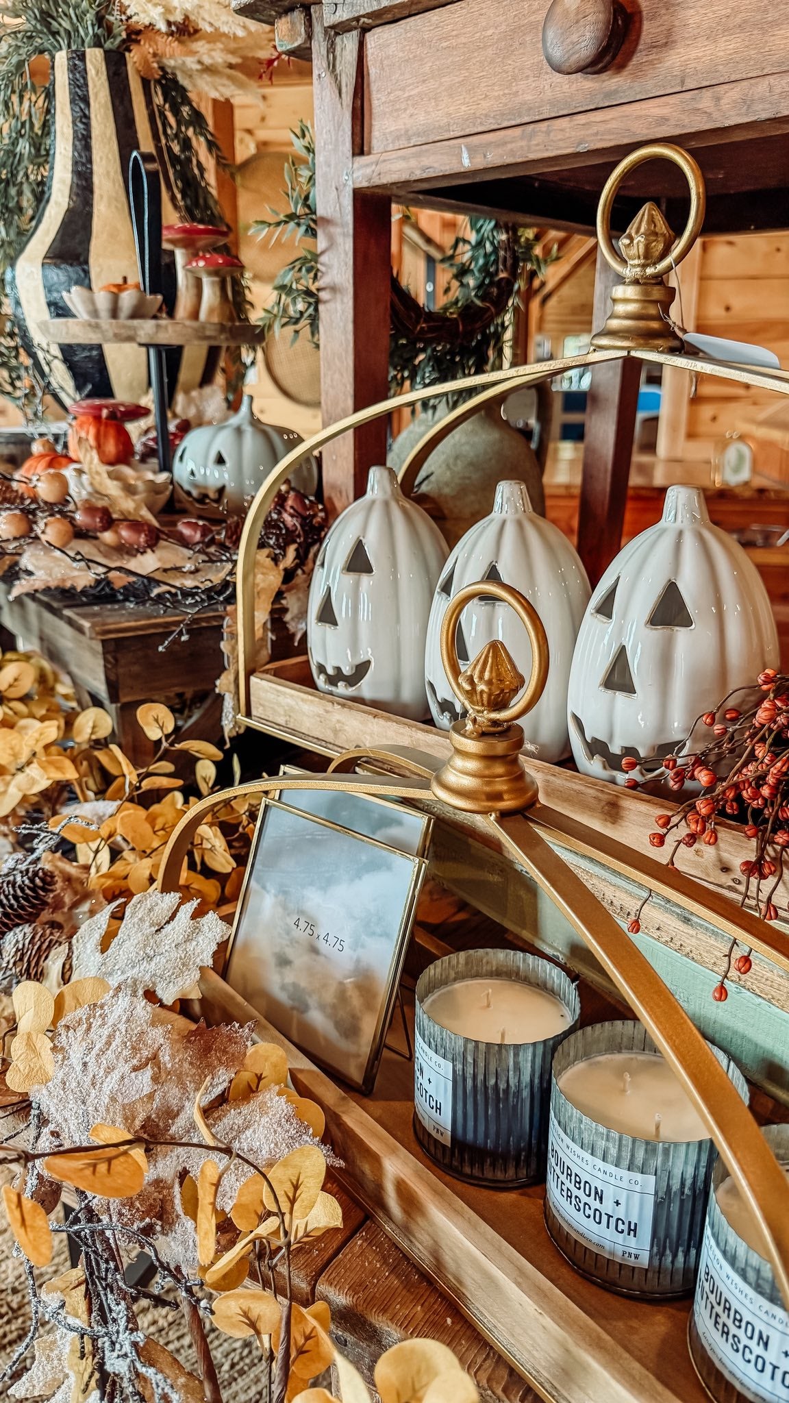 Decorative setup with pumpkins, candles, and a mirror on a wooden surface.